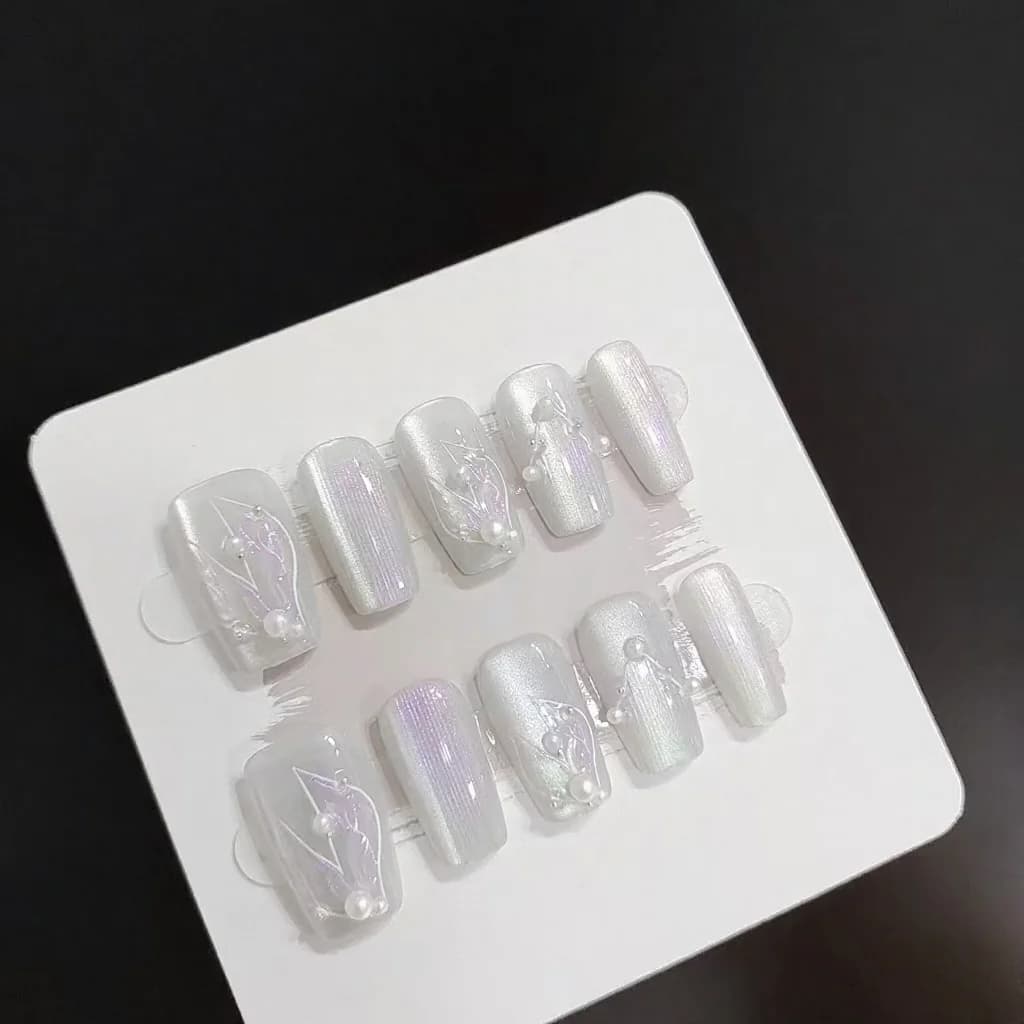 Unghii false argintii-albe tip sirena și „ochi de pisică” cu perle