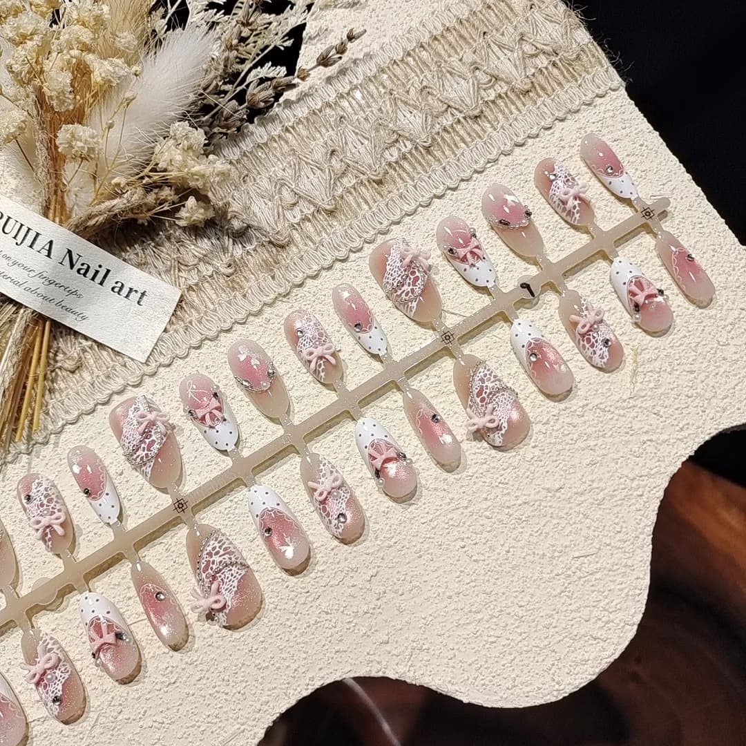 Unghii false roz satin cu efect Cat Eye, fundiță și pietre prețioase